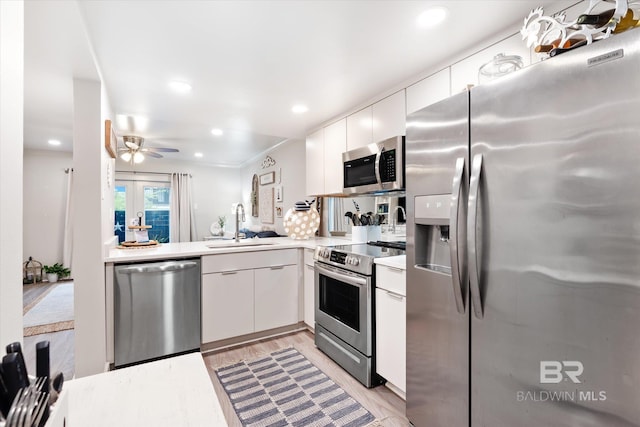 kitchen with ceiling fan, light hardwood / wood-style floors, stainless steel appliances, sink, and white cabinets