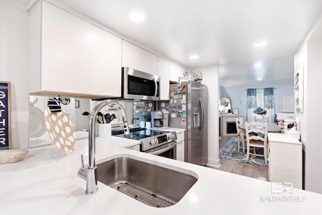 kitchen featuring white cabinets, appliances with stainless steel finishes, and light hardwood / wood-style floors