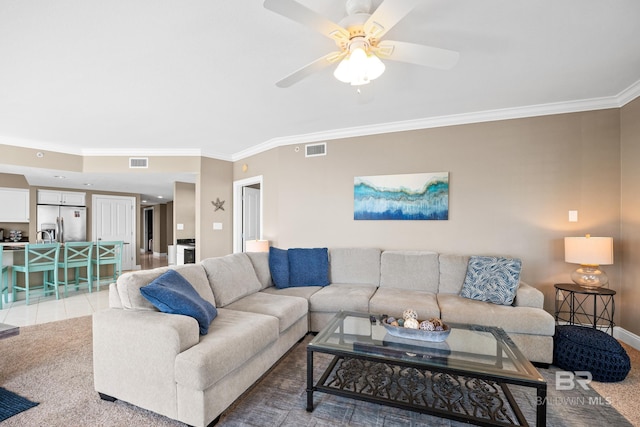 living area featuring visible vents, light colored carpet, ornamental molding, and a ceiling fan