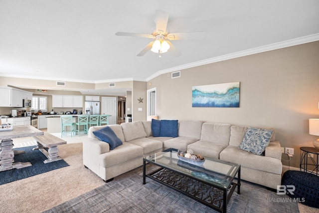 living room with a ceiling fan, visible vents, and ornamental molding