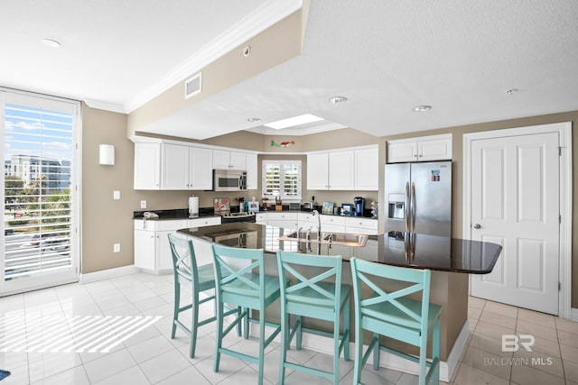 kitchen with visible vents, a sink, white cabinetry, appliances with stainless steel finishes, and crown molding