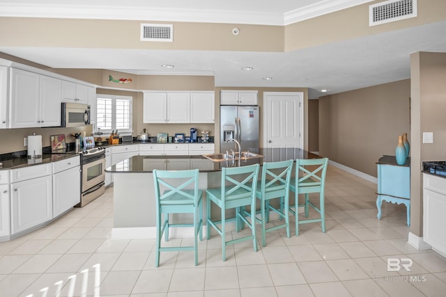 kitchen with dark countertops, ornamental molding, visible vents, and stainless steel appliances