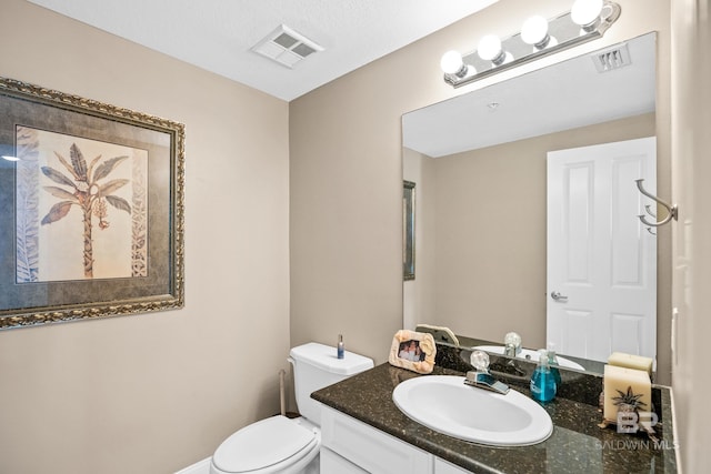 bathroom featuring visible vents, toilet, and vanity