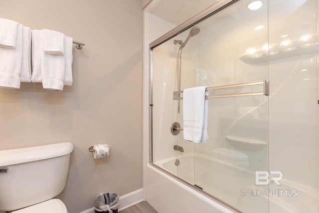 full bath with toilet, baseboards, and bath / shower combo with glass door