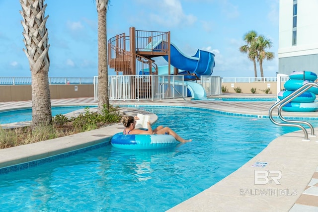 community pool with fence and a water slide