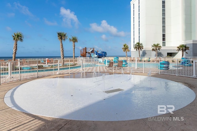 community pool featuring a water view and fence