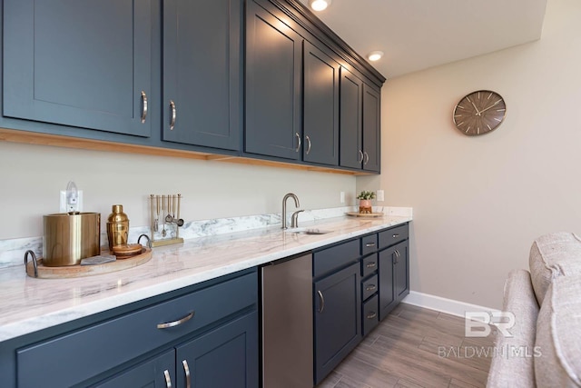 interior space featuring a sink, fridge, baseboards, and wood finished floors