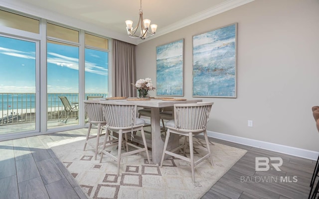 dining room with baseboards, ornamental molding, expansive windows, an inviting chandelier, and wood finished floors