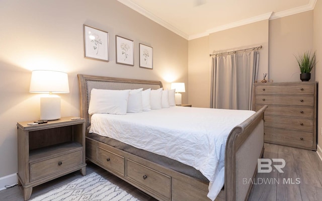 bedroom with light wood-style flooring, crown molding, and baseboards