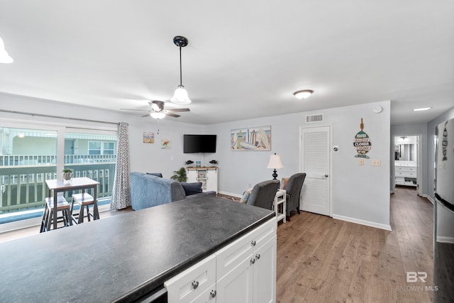 kitchen featuring ceiling fan, light wood-type flooring, white cabinetry, and decorative light fixtures