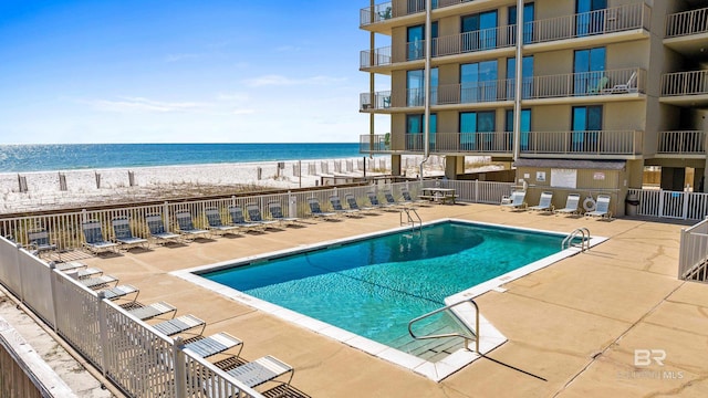 view of pool featuring a water view and a view of the beach