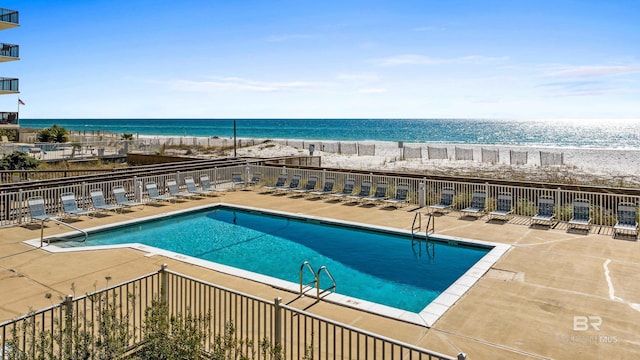 view of swimming pool with a beach view, a patio, and a water view