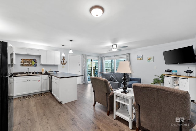 kitchen featuring white cabinets, black fridge, sink, ceiling fan, and decorative light fixtures