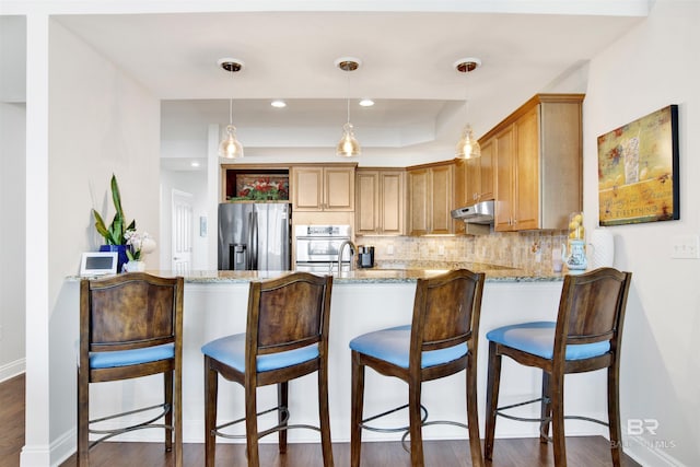 kitchen featuring stainless steel appliances, a peninsula, backsplash, and under cabinet range hood