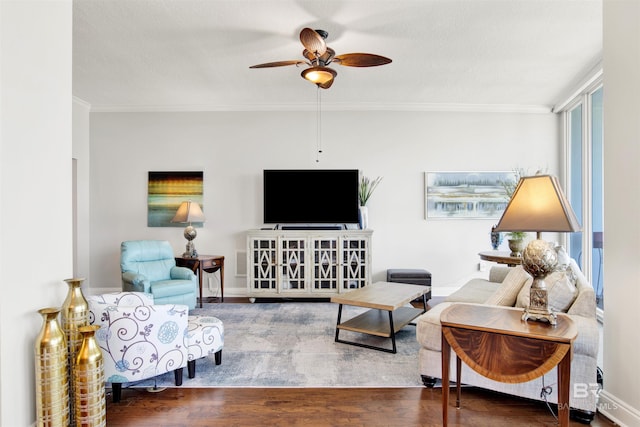 living room featuring ceiling fan, crown molding, baseboards, and wood finished floors