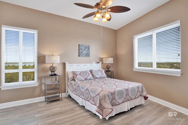 bedroom featuring light wood-style flooring, multiple windows, baseboards, and ceiling fan