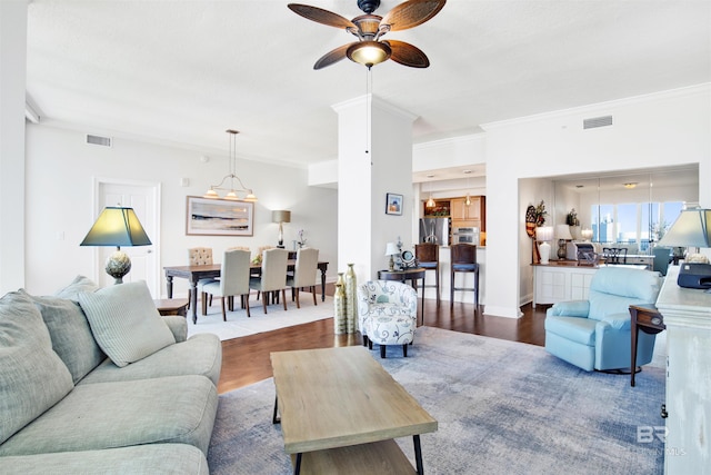 living area featuring ornamental molding, wood finished floors, and visible vents