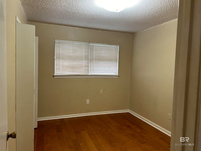 empty room with a textured ceiling and dark hardwood / wood-style flooring