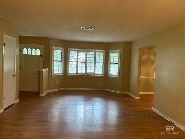 interior space with a textured ceiling and hardwood / wood-style floors