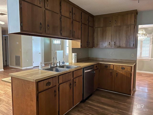 kitchen featuring dark wood-type flooring, sink, kitchen peninsula, an inviting chandelier, and stainless steel dishwasher