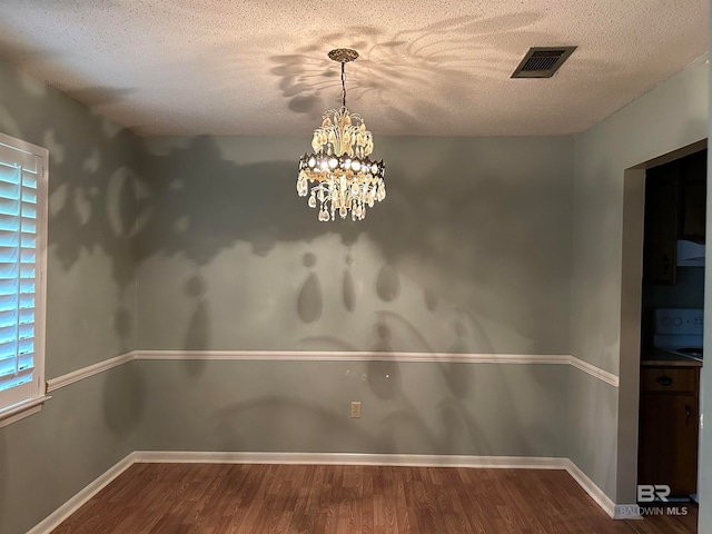 unfurnished dining area with wood-type flooring, a chandelier, and a textured ceiling