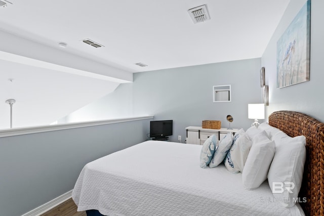 bedroom with vaulted ceiling with beams and hardwood / wood-style flooring