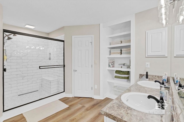 full bath featuring a sink, double vanity, a shower stall, and wood finished floors