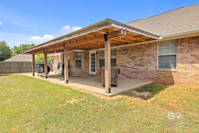 rear view of property with brick siding, a patio, fence, and a lawn