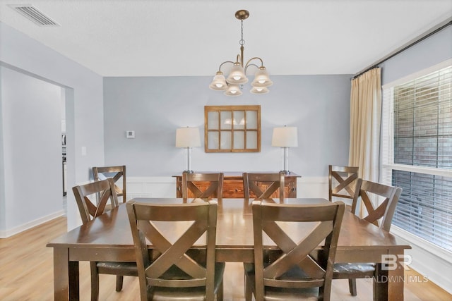 dining space featuring light wood-type flooring, a chandelier, and visible vents