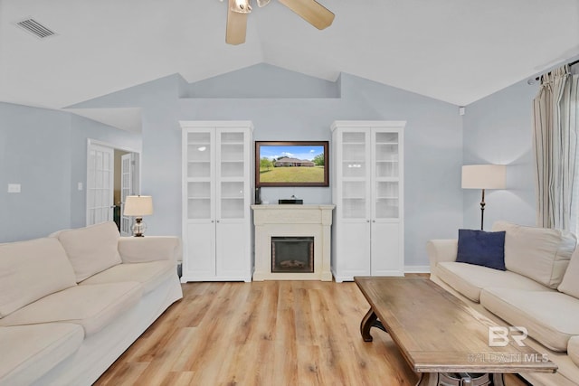 living room with visible vents, lofted ceiling, a fireplace, ceiling fan, and light wood-type flooring