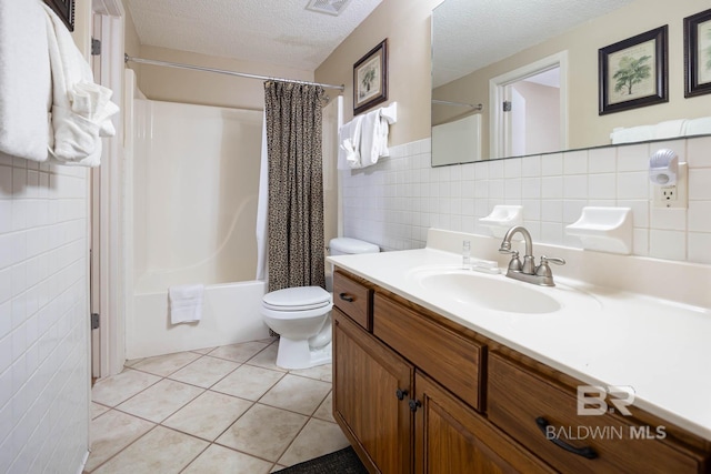 full bathroom with tile walls, shower / tub combo, toilet, tile patterned floors, and a textured ceiling