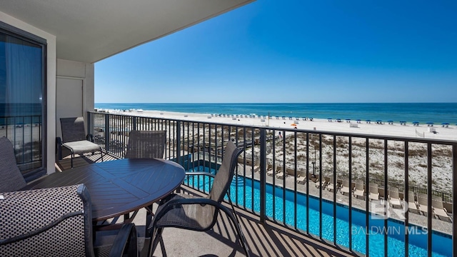 balcony with a water view and a view of the beach