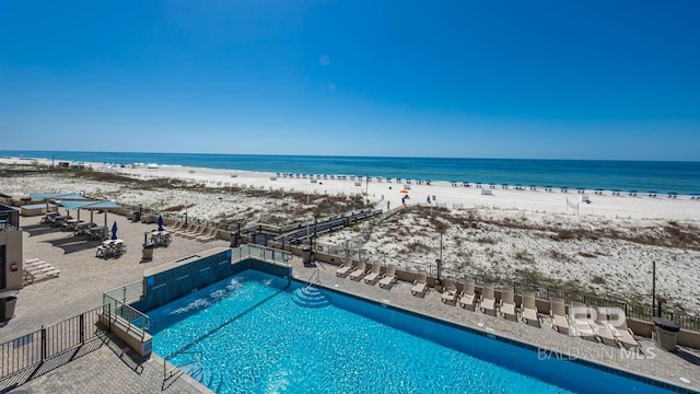 view of pool featuring a water view and a view of the beach