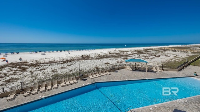 view of pool featuring a water view and a view of the beach