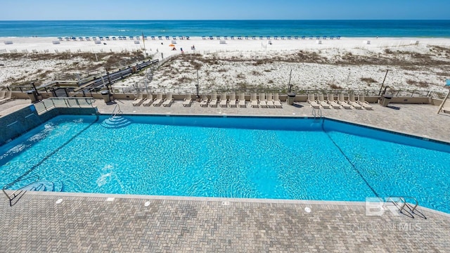 view of pool featuring a water view and a beach view