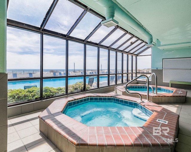 view of pool with an indoor hot tub and a water view