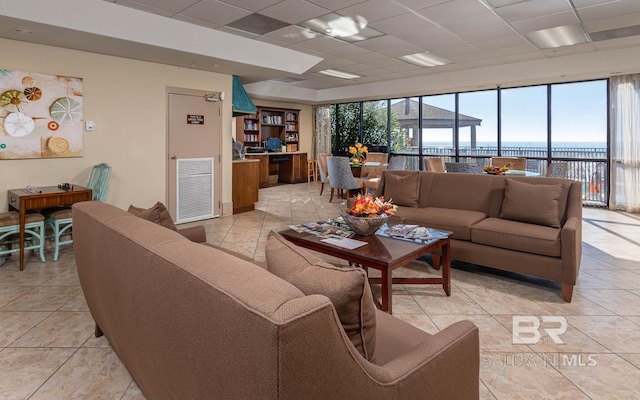 tiled living room with a water view, plenty of natural light, and a paneled ceiling