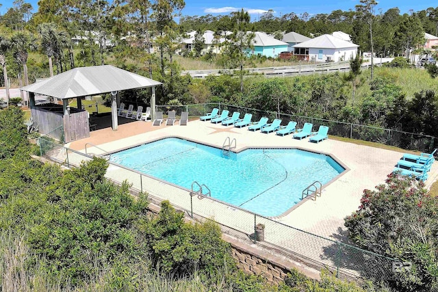 pool with a patio, fence, and a gazebo