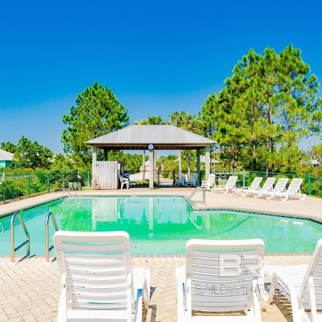 pool with a gazebo, fence, and a patio