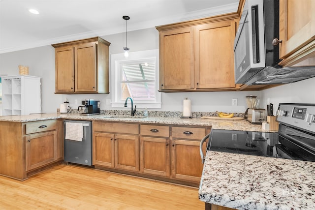 kitchen featuring brown cabinets, a sink, a peninsula, light wood-style floors, and stainless steel appliances