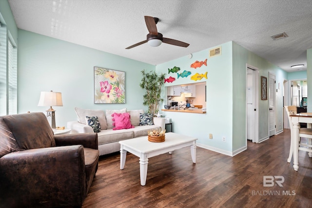 living room featuring ceiling fan, a textured ceiling, and dark wood-type flooring