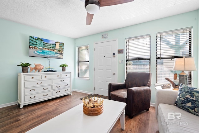 living room with ceiling fan, a textured ceiling, dark wood-type flooring, and a healthy amount of sunlight