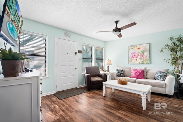 living room with ceiling fan, a textured ceiling, dark hardwood / wood-style flooring, and a healthy amount of sunlight