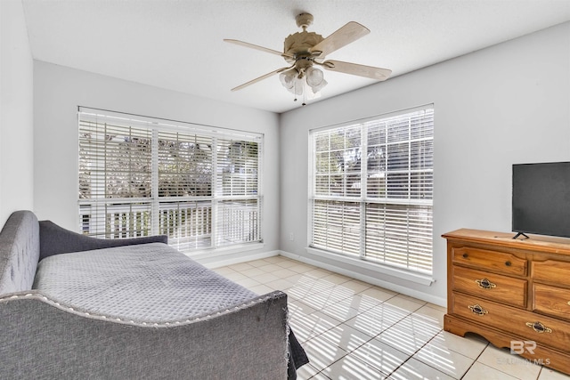 bedroom featuring ceiling fan, light tile patterned floors, and multiple windows