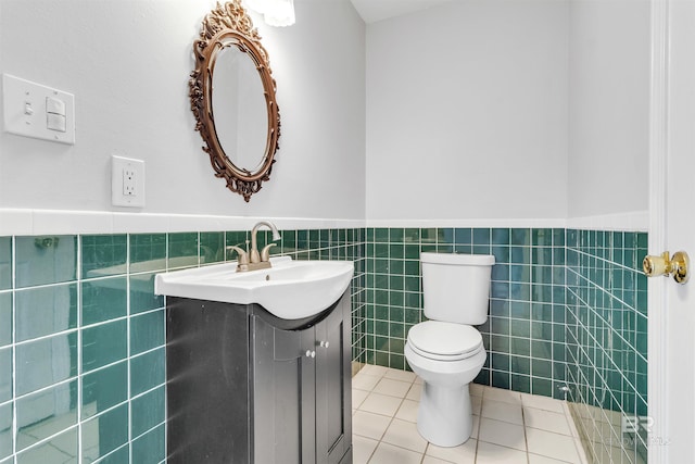 bathroom featuring tile patterned flooring, vanity, toilet, and tile walls