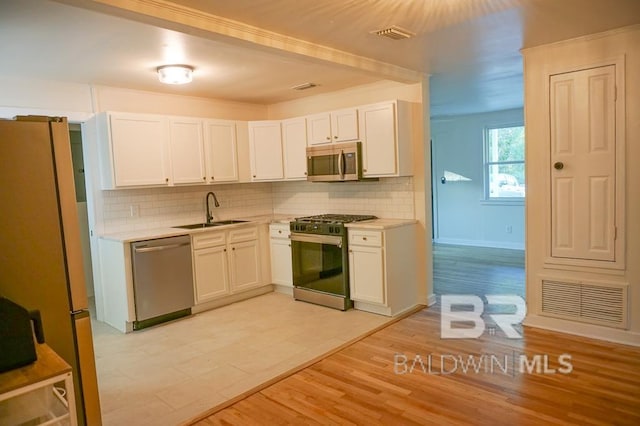 kitchen with appliances with stainless steel finishes, tasteful backsplash, white cabinetry, and sink