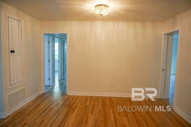 spare room with an inviting chandelier and light wood-type flooring