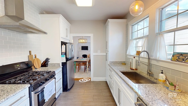 kitchen with decorative backsplash, stainless steel appliances, white cabinetry, wall chimney exhaust hood, and a sink