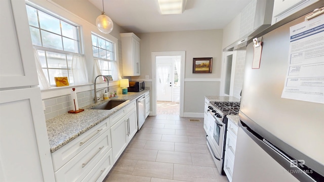 kitchen with decorative backsplash, white cabinets, stainless steel appliances, wall chimney exhaust hood, and a sink