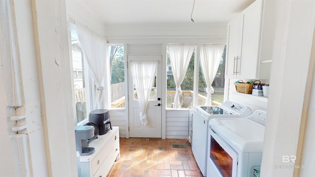 washroom featuring laundry area, washer and dryer, and brick floor